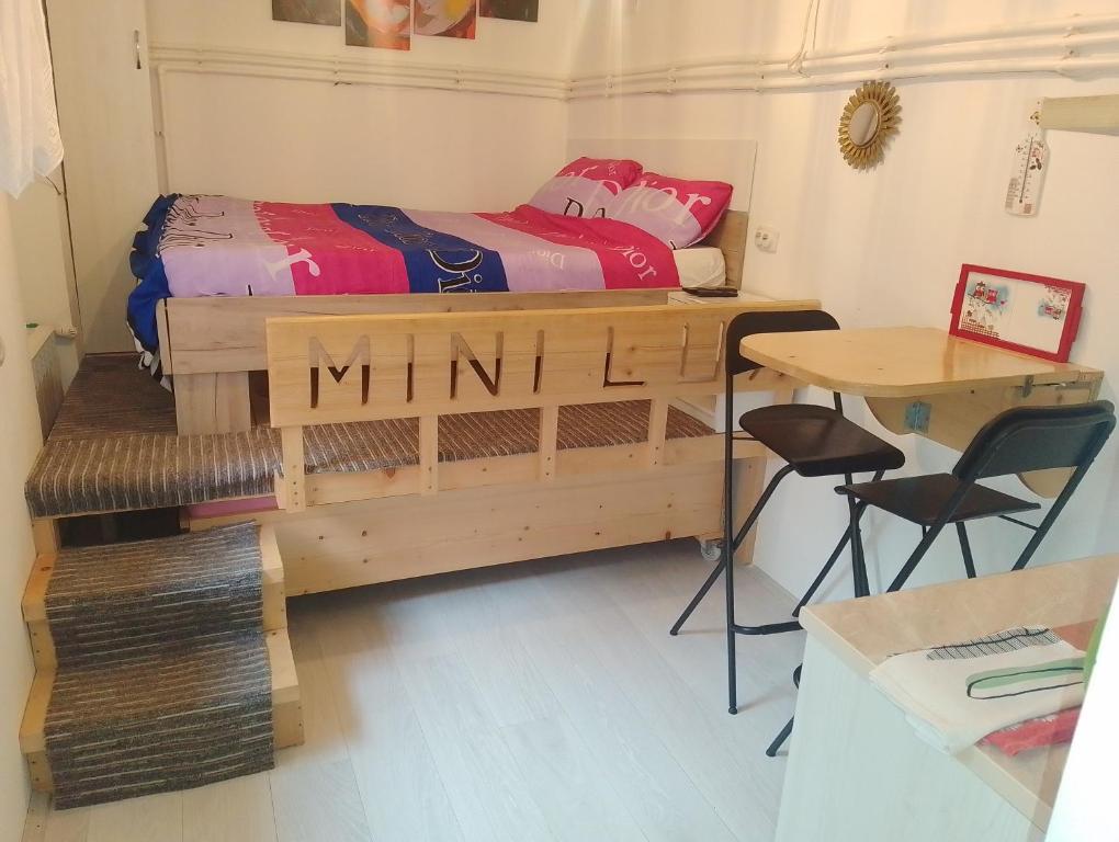 a small bedroom with a bed and a desk and a table at Studio Mini Lux in Požarevac