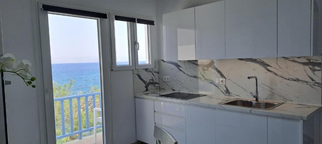 uma cozinha com um lavatório e vista para o oceano em Dinas Inn em Piso Livadi