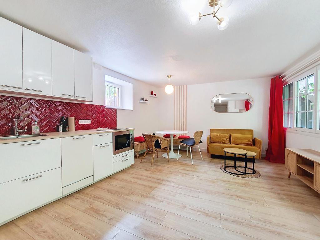 une cuisine avec des placards blancs et un salon avec une table dans l'établissement T2 Cosy - Hypercentre - NEW SOFA BED - Cathédrale - Carré d'OR, à Strasbourg