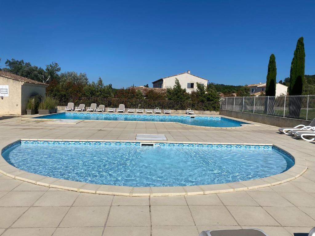 a large swimming pool with chairs in a patio at Au pied des Alpilles in Paradou