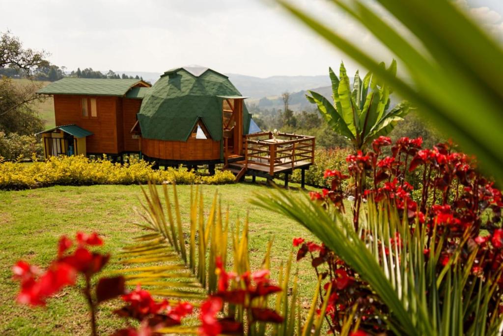 VillapinzónにあるGlamping - Domo el Frailejón con Jacuzziの庭の花とベンチ付きの家