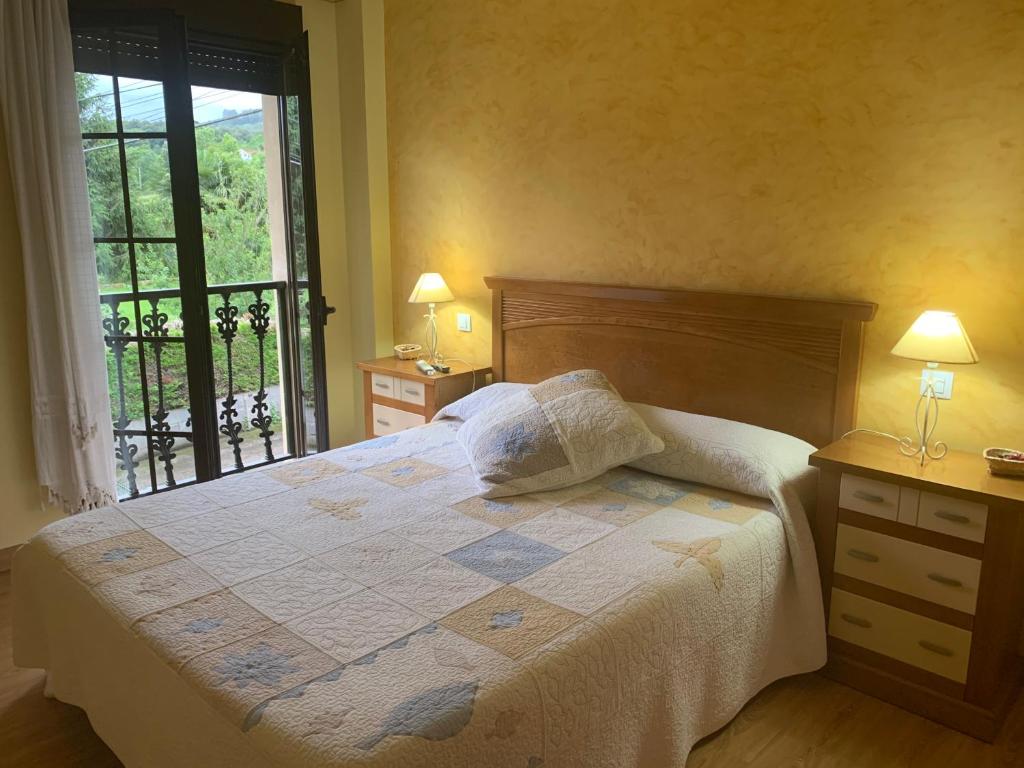 1 dormitorio con 1 cama con 2 lámparas y una ventana en posada carral cabarceno en La Concha