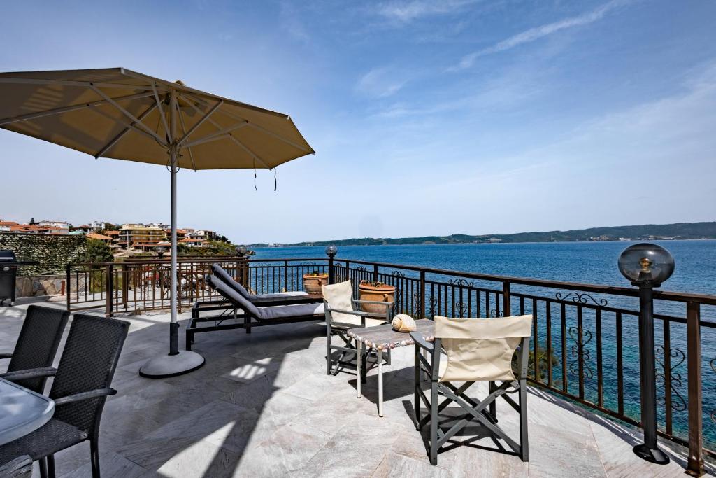a patio with chairs and an umbrella and the water at Villa Chara in Ammouliani