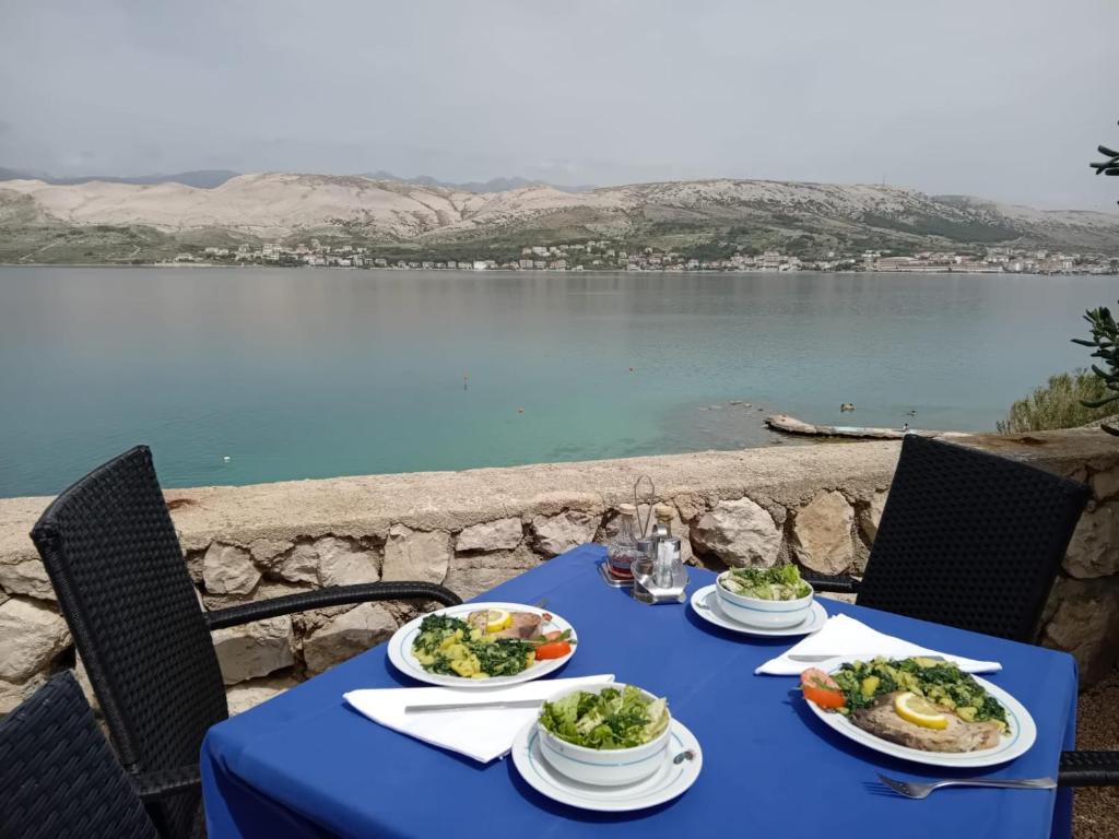 Hotel Biser في باغ: طاولة زرقاء عليها صحون طعام بجوار بحيرة