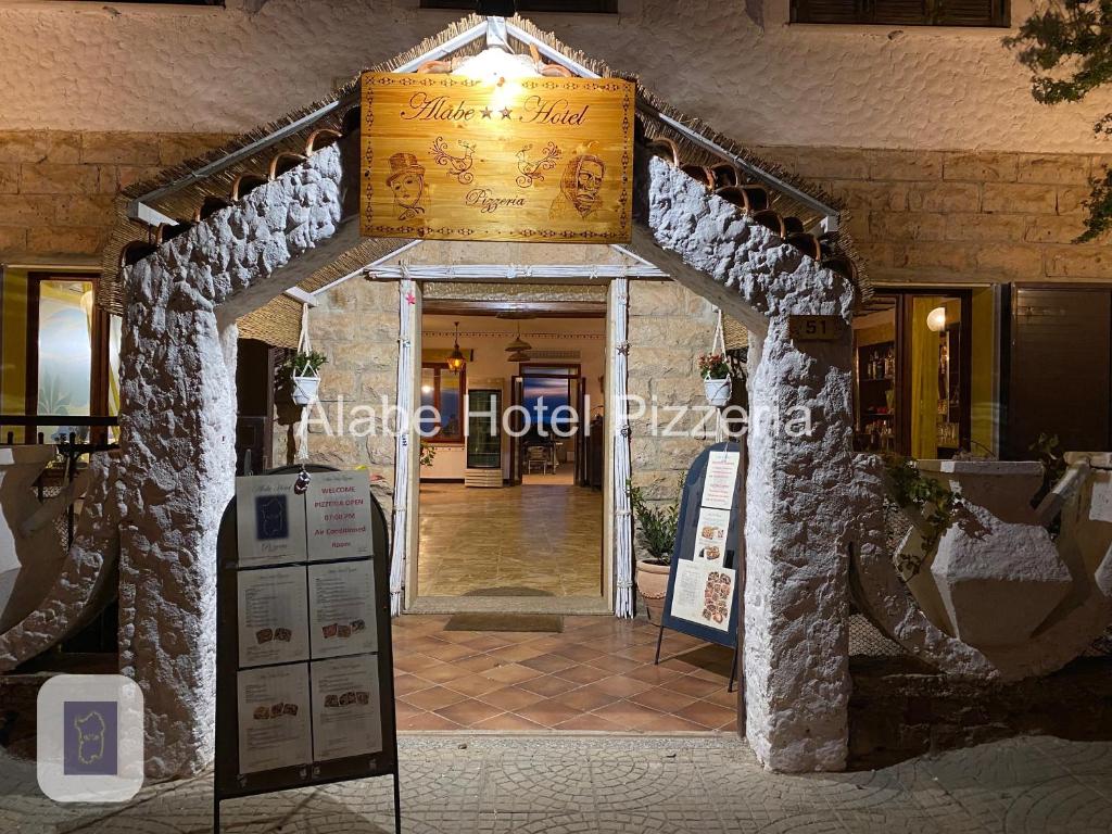 Alabe Hotel في Tresnuraghes: مدخل لمبنى فيه لافته امامه