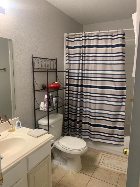 uma casa de banho com um WC e uma cortina de chuveiro em Private Cozy Lock Room 1 em Cypress