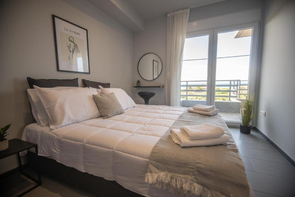 a bedroom with a large bed with a large window at Relax Apartments in Alexandroupoli