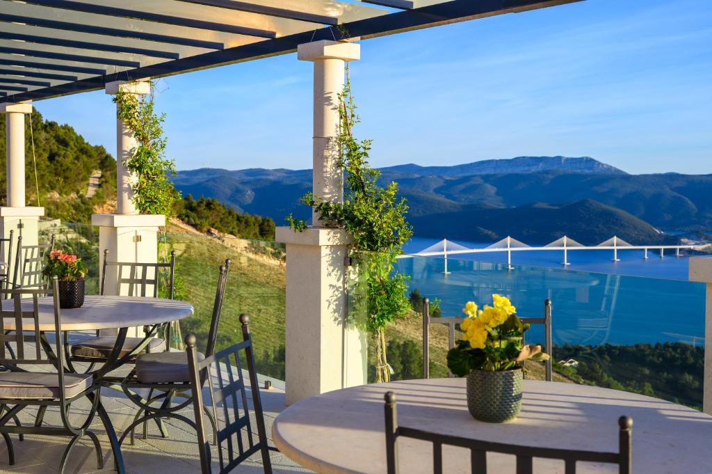 a patio with tables and chairs and a view of the water at Winery Rizman B&B in Slivno Ravno