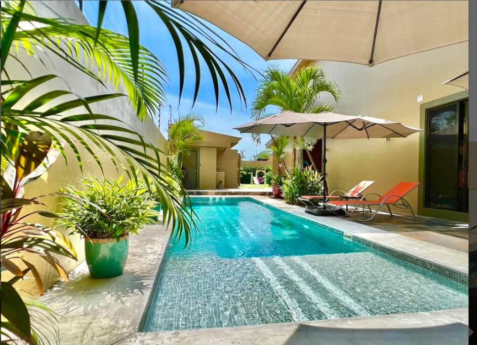 einen Pool in einer Villa mit Sonnenschirm in der Unterkunft Villa Gucci Luxury Manuel Antonio w Pool in Manuel Antonio