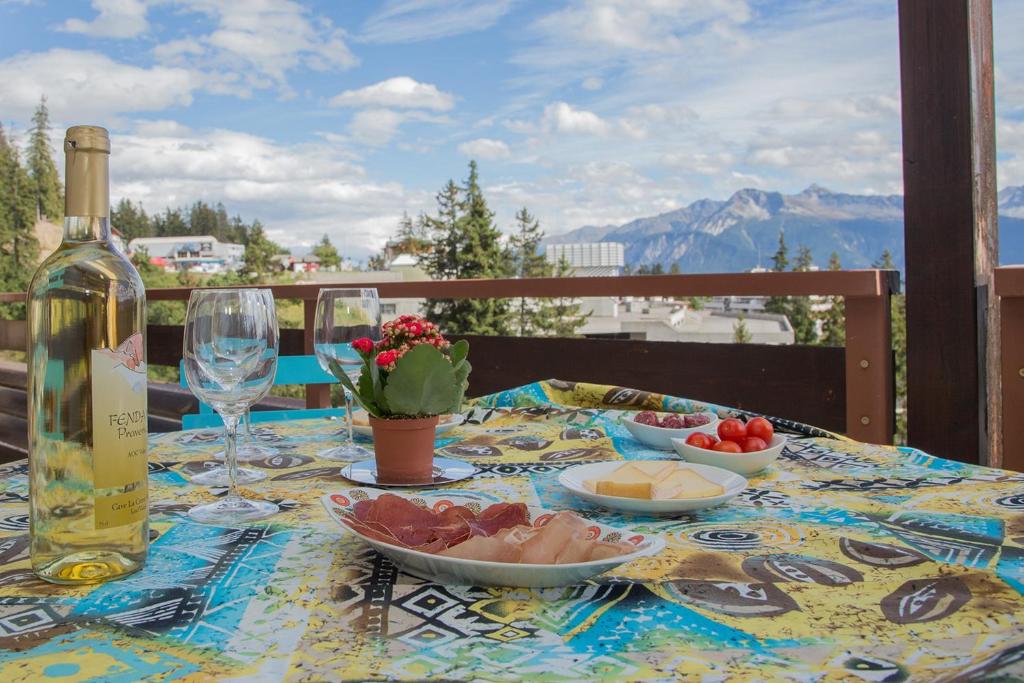 una mesa con una botella de vino y platos de comida en La Marmotte, au cœur du village de Crans, proche du télécabine Cry d'Er, en Crans-Montana