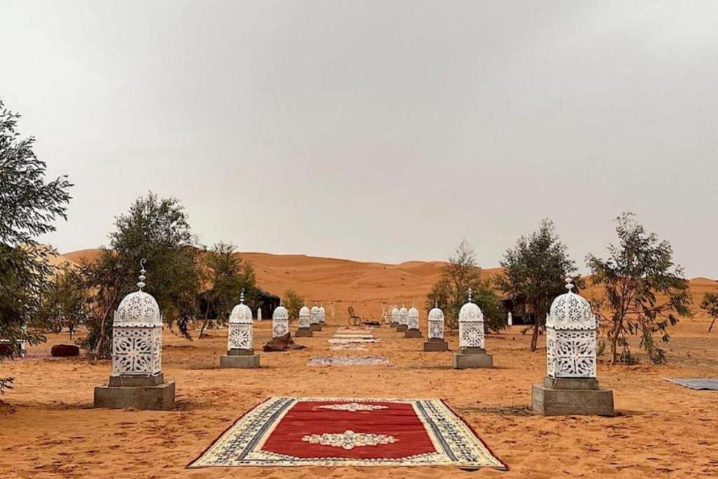 a row of gravestones in the desert with a red carpet at Sahara Desert Camp in Merzouga
