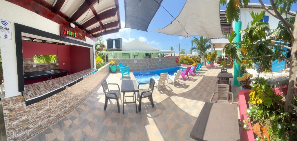 un patio del resort con tavoli, sedie e piscina di Posada Ashanty a Providencia