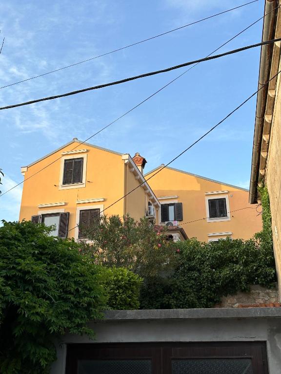 a yellow house with a fence in front of it at Apartments Cunski in Čunski