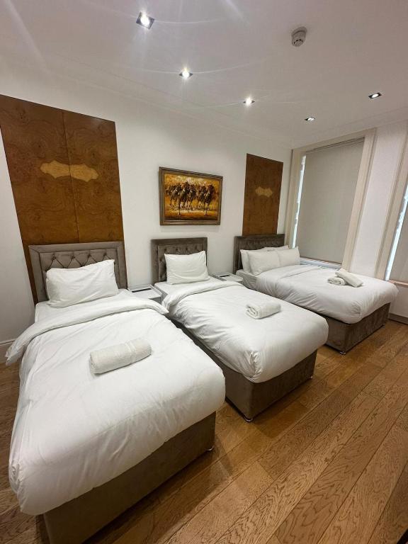 Zimmer mit 4 Betten und weißer Bettwäsche in der Unterkunft The Chapter Hotels - Mayfair Residences in London