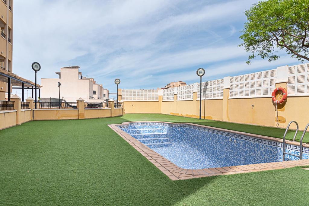 a swimming pool with green grass next to a building at AT Tino Casal in Almería