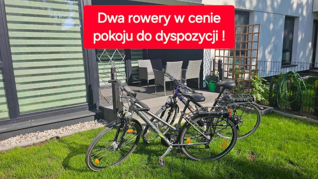 deux vélos garés à côté d'un panneau dans l'herbe dans l'établissement Apartament Mono Ełk CENTRUM, à Ełk