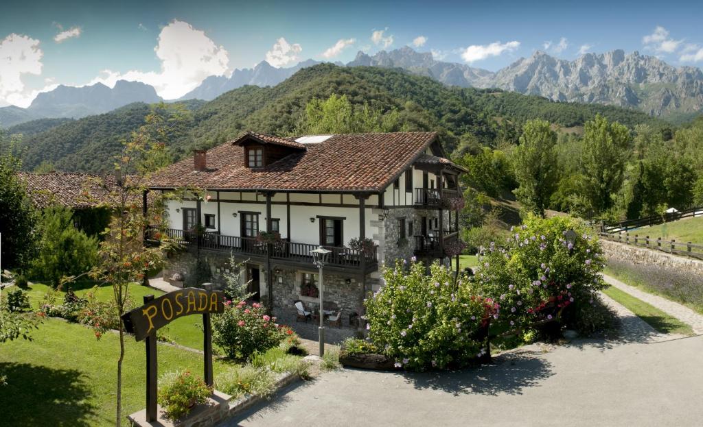 une maison sur une colline avec des montagnes en arrière-plan dans l'établissement Posada San Pelayo, à Camaleño