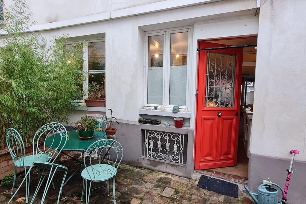 une table et des chaises devant une maison avec une porte rouge dans l'établissement Originale maison individuelle au coeur de Paris !, à Paris