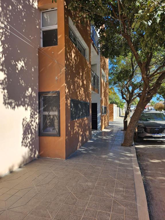 un trottoir devant un bâtiment avec un arbre dans l'établissement Center Cruz del Eje, à Cruz del Eje