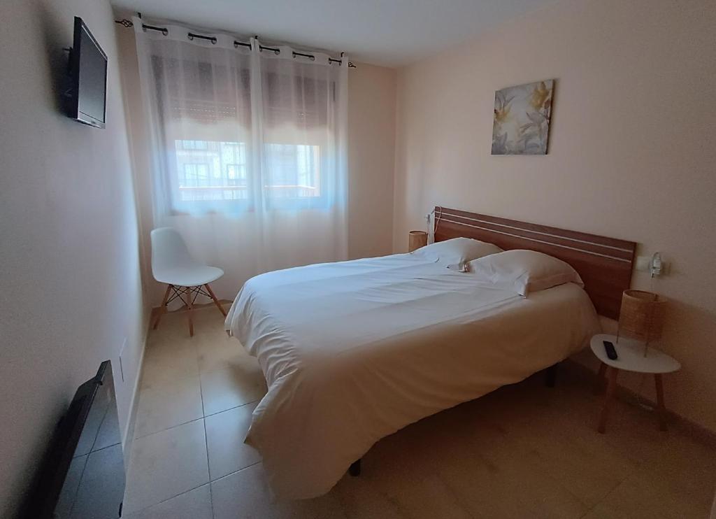 a bedroom with a bed and a chair and a window at Apartamento San Martín in Sanxenxo