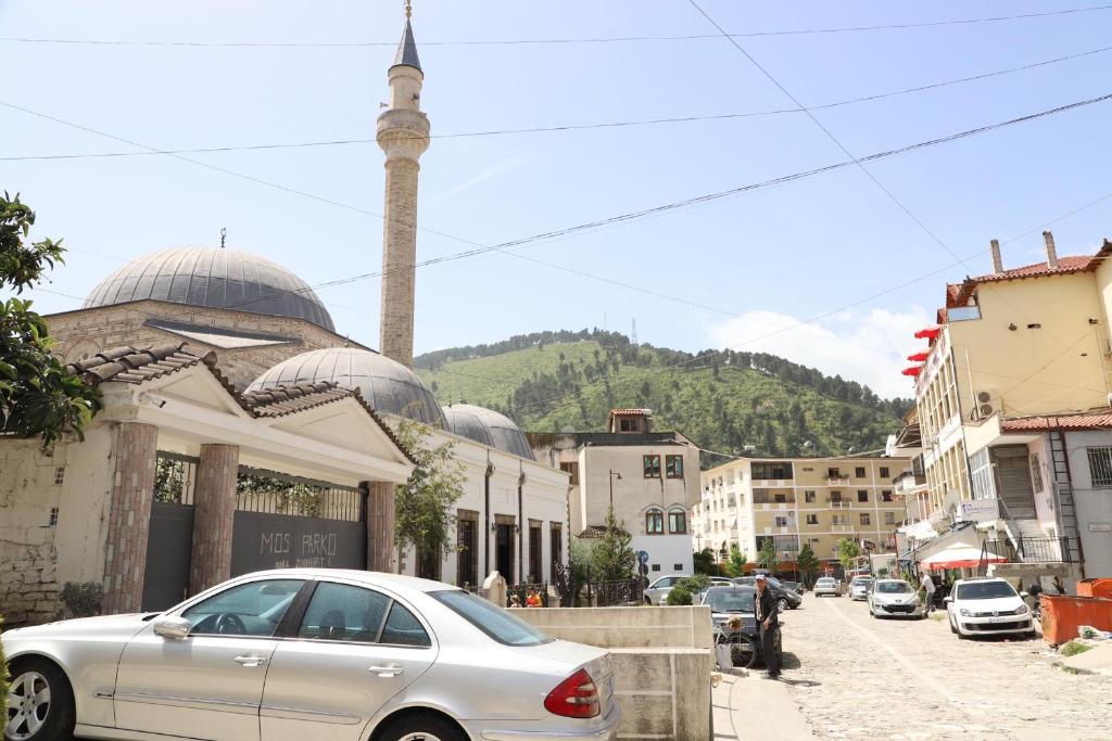 a silver car parked on a street with a mosque at Guesthouse N&B in Berat