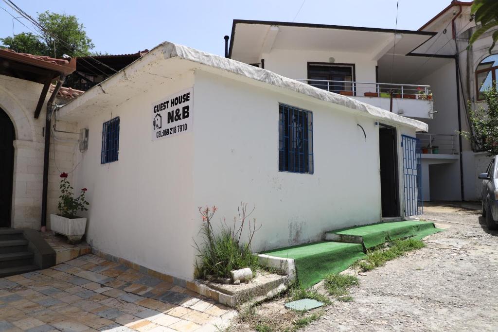 a white house with a green lawn in front of it at Guesthouse N&B in Berat