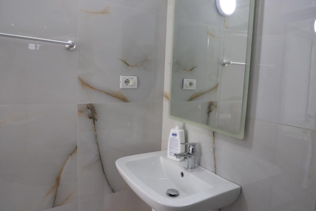 a white bathroom with a sink and a mirror at Guesthouse N&B in Berat