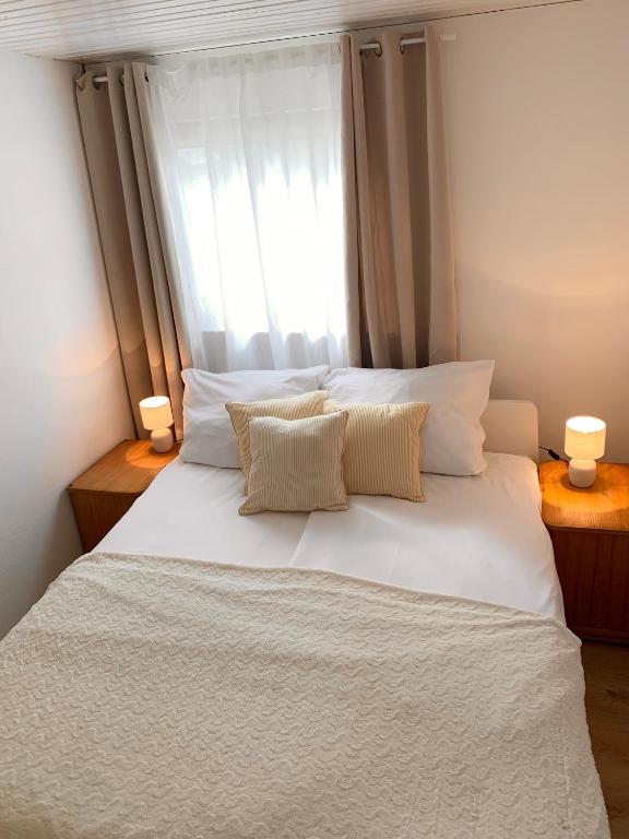 a white bed with two pillows and a window at Ferienwohnung Zumhof in Rudersberg