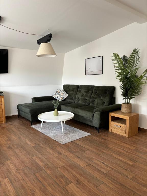 Stadtapartment KUS في كلاغنفورت: غرفة معيشة مع أريكة خضراء وطاولة