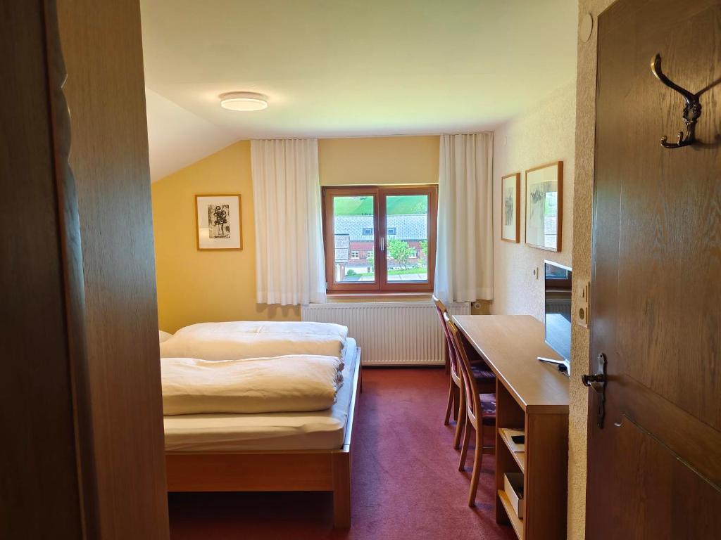 um quarto com uma cama, uma secretária e uma mesa em Pension Zita em Schoppernau