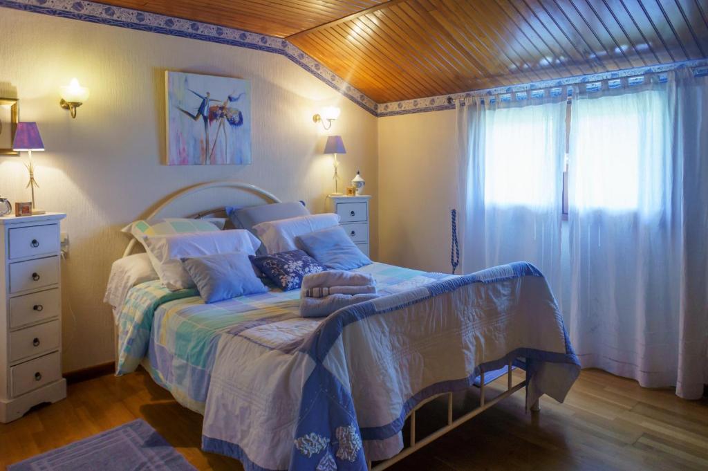 - une chambre avec un lit doté de draps bleus et une fenêtre dans l'établissement Chez Pepette et Serge, à Montdragon