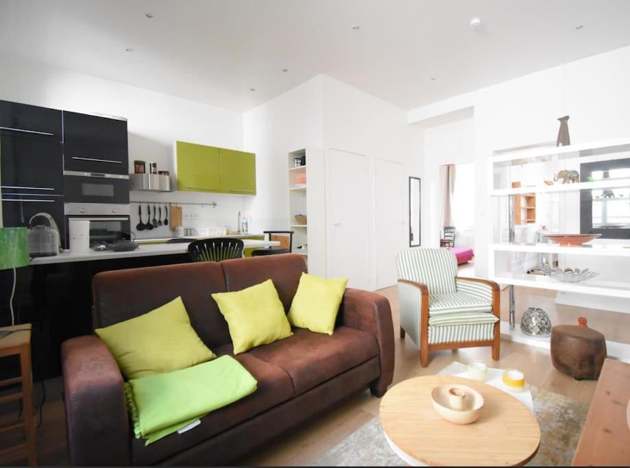 un salon avec un canapé marron avec des coussins jaunes dans l'établissement LE COUTURIER - Hyper Centre - Rez de Chaussée - Prox Thermes, à Vichy