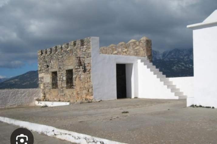 a white building with a door and stairs on a street at house FYNTIKAKH - SKALA in Anopoli Sfakion