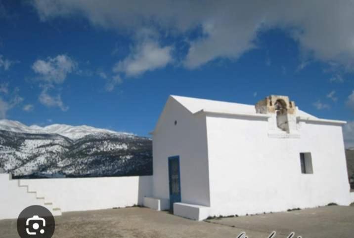 a small white church with snowy mountains in the background at house FYNTIKAKH - SKALA in Anopoli Sfakion