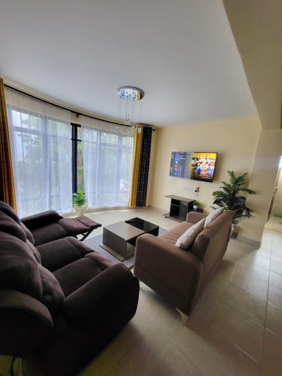 - un salon avec deux canapés et une télévision dans l'établissement G&G Homes Executive One Bedroom, à Nakuru