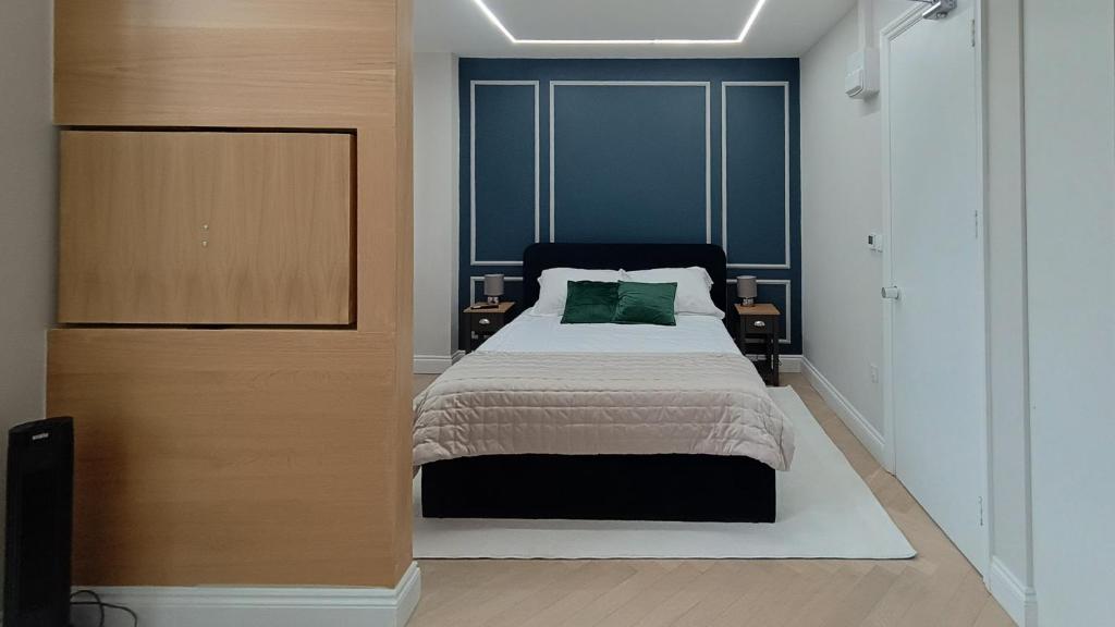 um quarto com uma cama com uma parede azul em London Studios and Suites em Harrow