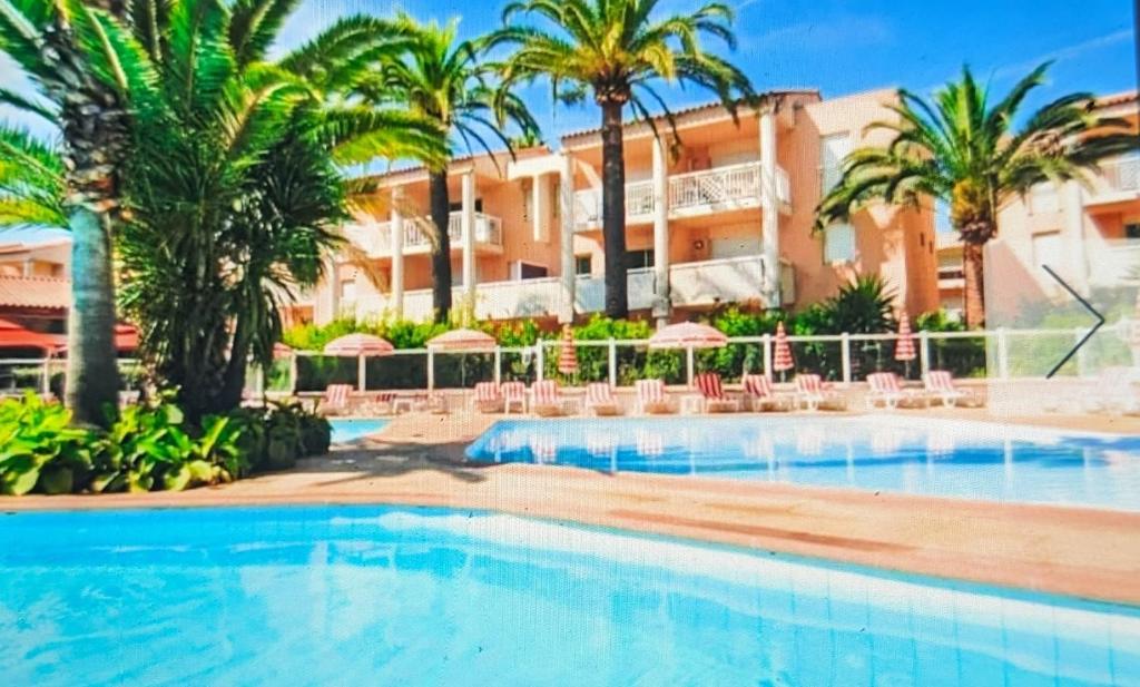 a swimming pool in front of a hotel with palm trees at Votre résidence de vacances avec piscine, tennis, à 2 minutes de la mer in Vallauris