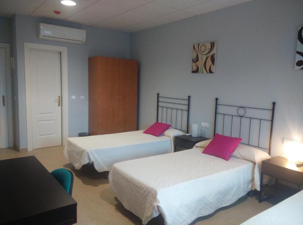 Habitación con 2 camas y almohadas rosas. en Hostal la Molina, en Álora