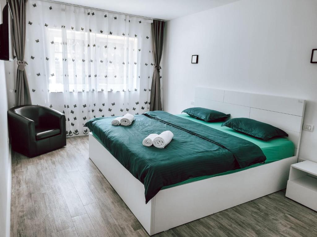 um quarto com uma cama com lençóis verdes e uma cadeira em Cosy apartment Fagaras em Făgăraş