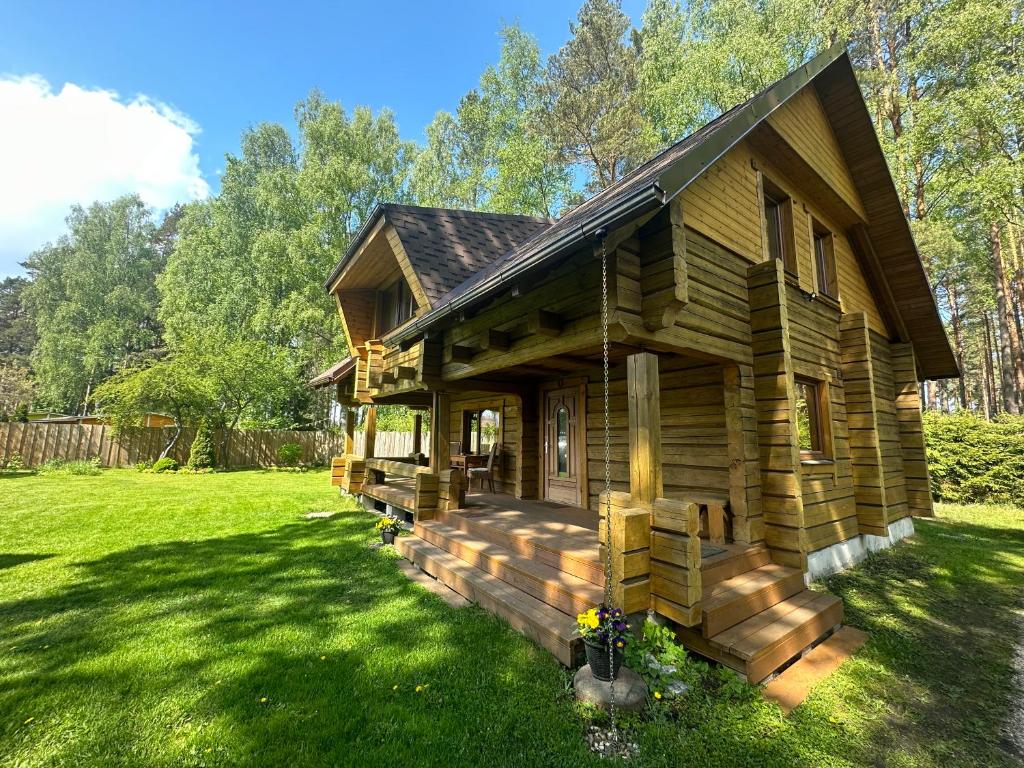 a log cabin in a yard with green grass at Guest house Saulainie krasti in Saulkrasti