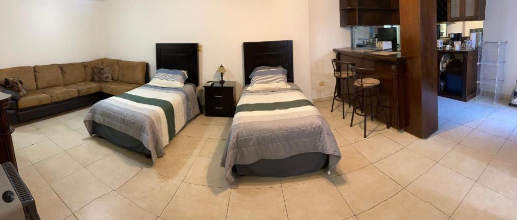 dwa łóżka w salonie z kanapą w obiekcie Loft con baño privado w mieście Monterrey