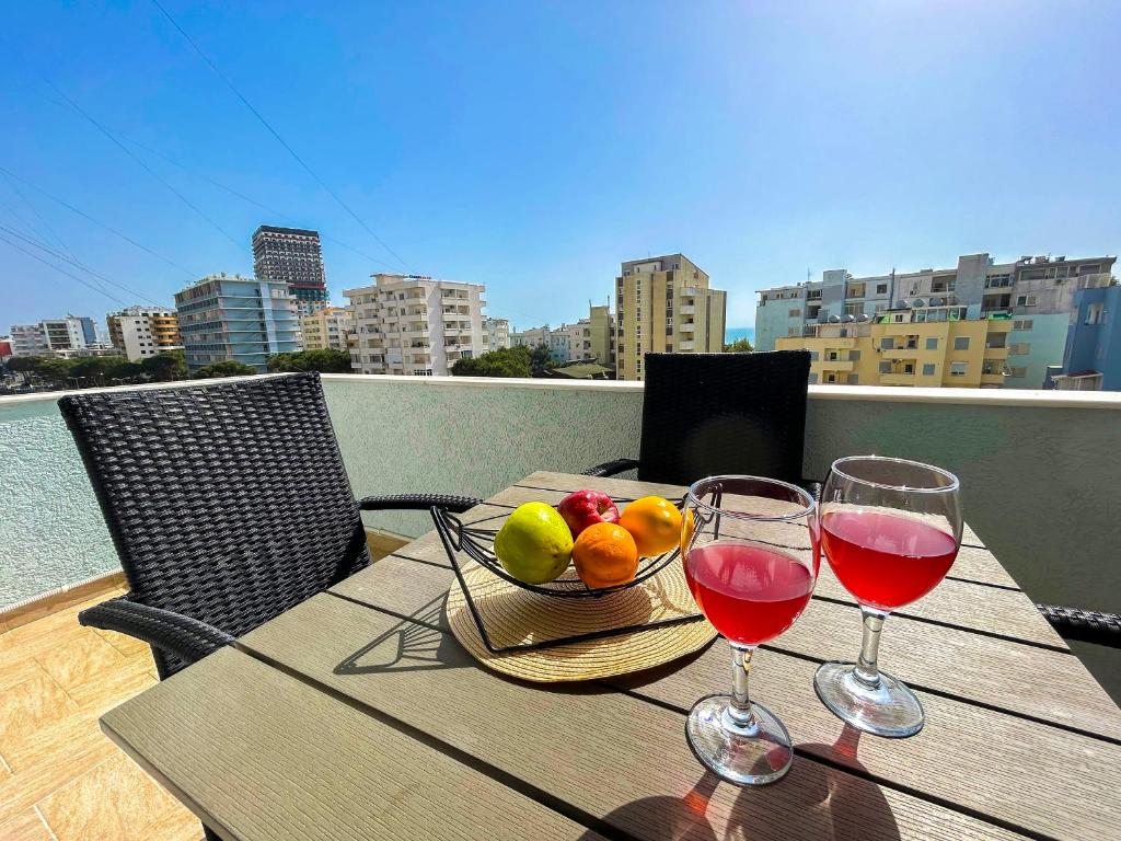 uma mesa com uma taça de fruta e dois copos de vinho em Vacation 893 em Durrës