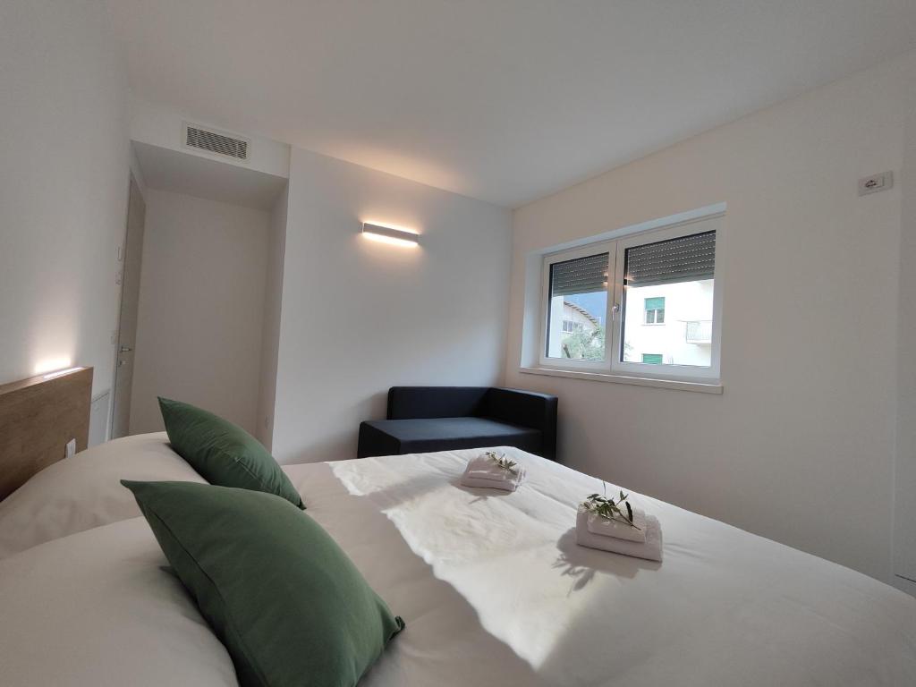 una camera da letto con un grande letto bianco con cuscini verdi di Oasi degli Ulivi a Riva del Garda