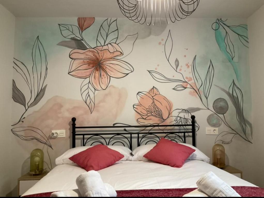 ein Schlafzimmer mit einem Bett mit einem Blumenbild an der Wand in der Unterkunft LA ANTIGUA CUADRA precioso apartamento de piedra con jardín, barbacoa y acceso al río in Ramales de la Victoria