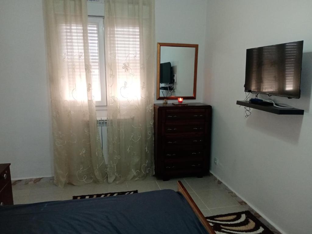 Appartement meublé في قسنطينة: غرفة نوم مع خزانة ومرآة وتلفزيون