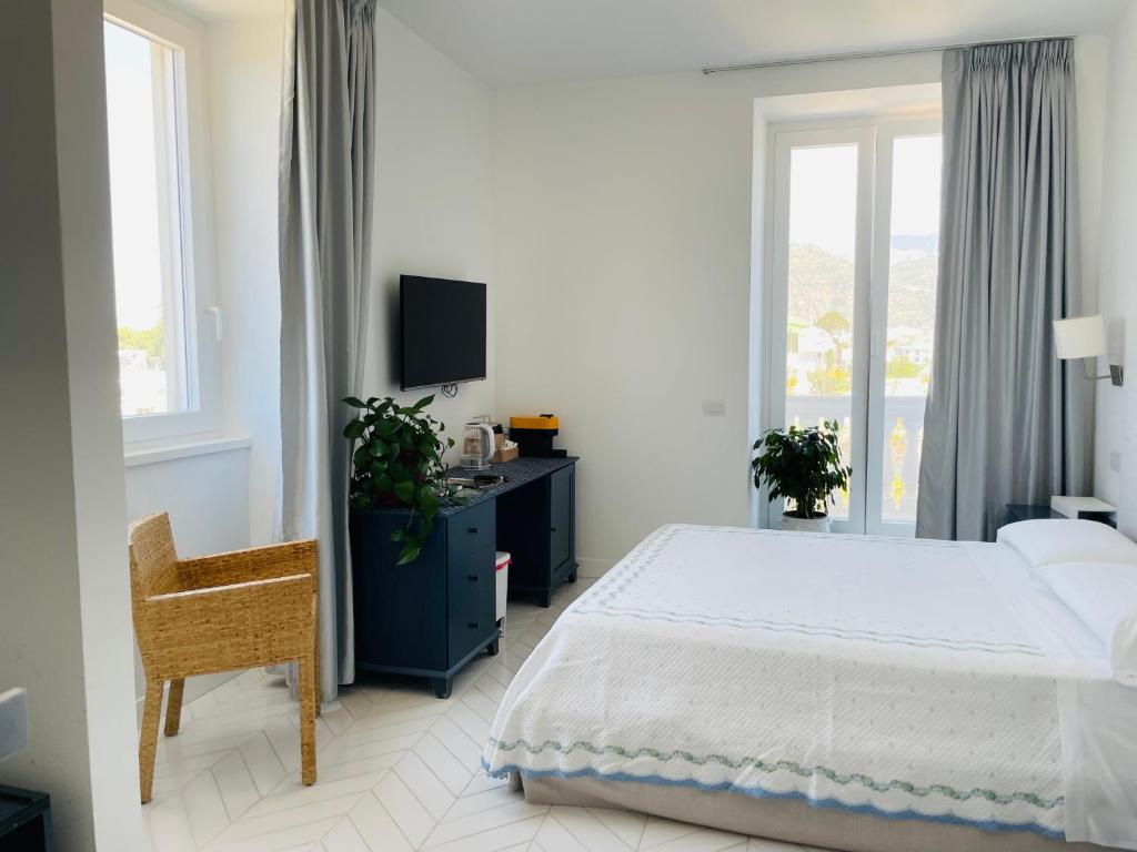 een witte slaapkamer met een bed, een bureau en een raam bij Casa Torre a Sorrento con parcheggio gratuito in Sorrento