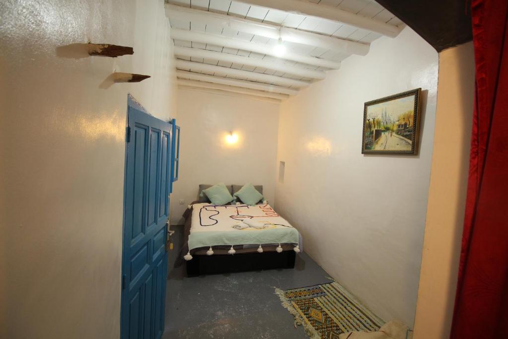 um pequeno quarto com uma cama com uma porta azul em ASARAG em Mirleft