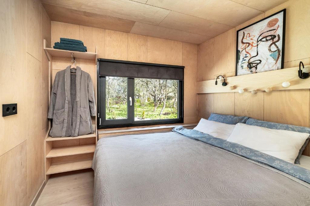 ein kleines Schlafzimmer mit einem Bett und einem Fenster in der Unterkunft A tiny house with a garden and a hot tube in Pringi