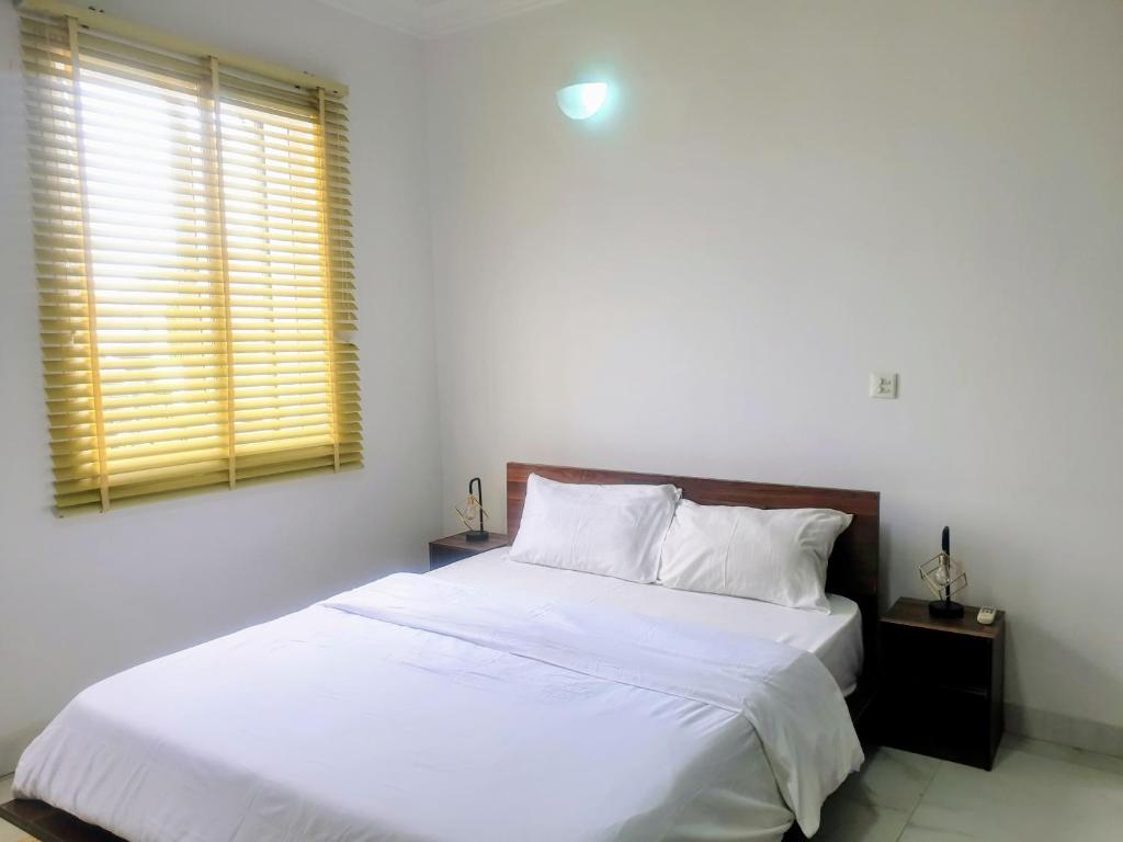 a bedroom with two beds with white sheets and a window at Oasis in the City. Victoria Island serviced apt. in Lagos