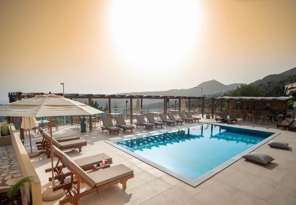 uma piscina com cadeiras e um guarda-sol num edifício em Maria Resort Parga em Parga